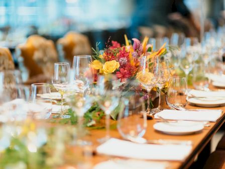 A beautifully set dining table featuring glassware, plates, and a vibrant floral centerpiece, ready for an elegant event or gathering.