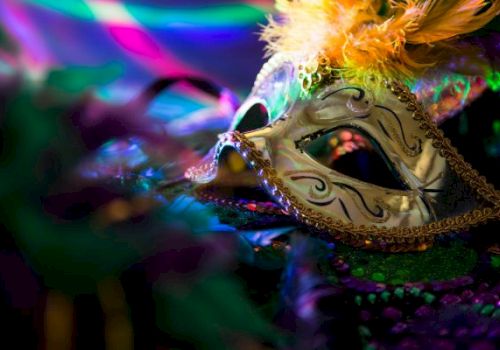 A ornate masquerade mask with gold filigree, feather accents, and colorful lighting, suggesting a festive carnival or masquerade theme.