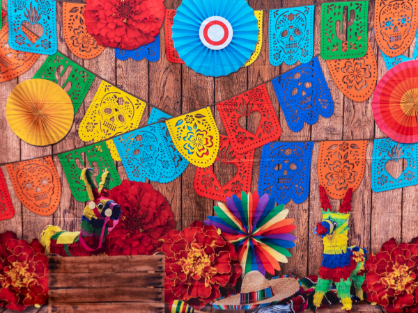 A festive scene with colorful papel picado banners, paper rosettes, and decorative pi&ntilde;atas against a wooden backdrop, vibrant and celebratory.