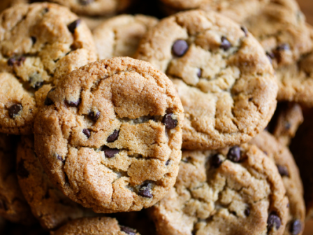 The image shows a pile of delicious, freshly baked chocolate chip cookies arranged closely together.