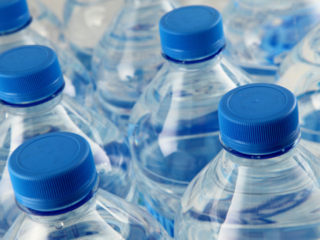 This image shows several plastic water bottles with blue caps, closely arranged together.