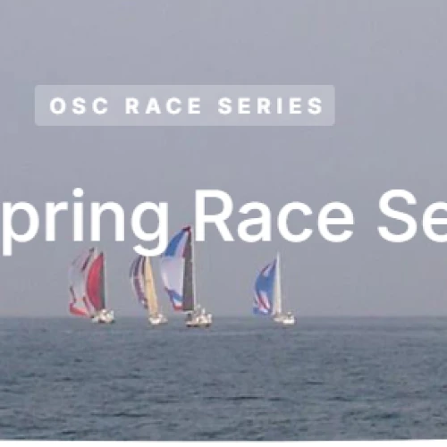 Sailboats compete in the OSC Spring Race Series on the open sea, with colorful sails against a clear sky in the background.