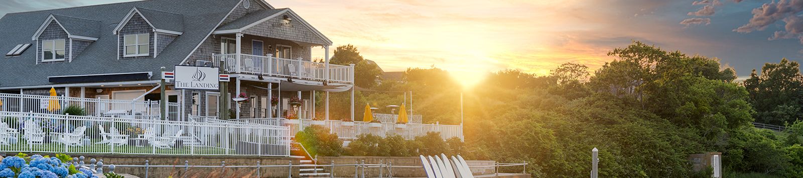 A lakeside resort with a white boardwalk and marina paddleboats at sunrise, glowing under dramatic clouds.