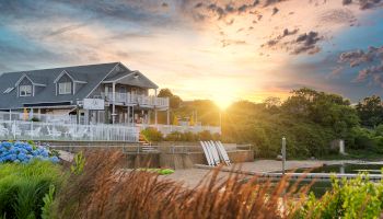 A hotel near a beachwith a beautiful sunset in the background, surrounded by greenery and flowers, creating a serene atmosphere.